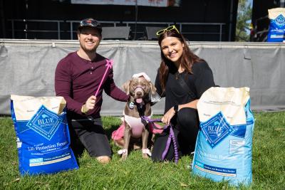 Couple with a dog between two bags of Blue Buffalo dog food