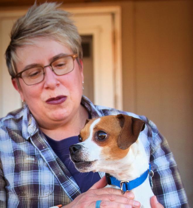 Smiling person sitting outside on steps with their dog