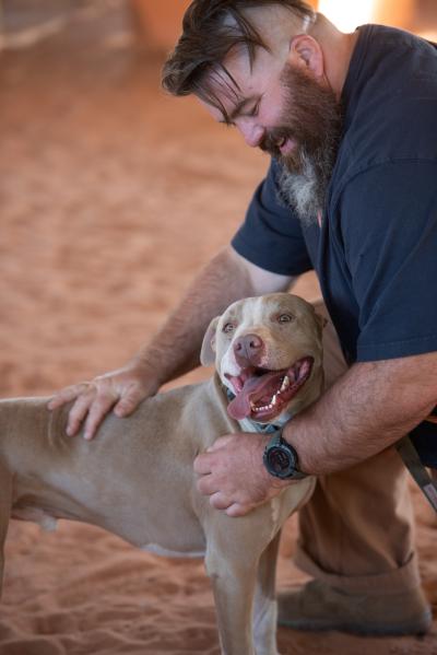 James kneeling down to pet Bonito the dog, who is smiling with his tongue out