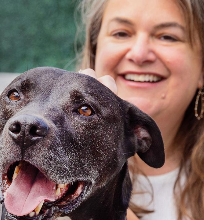 Smiling person with happy black dog in front of her