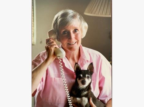 Best Friends co-founder Charity Rennie on a phone with a small dog in her lap