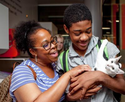 Two people smiling while holding a kitten