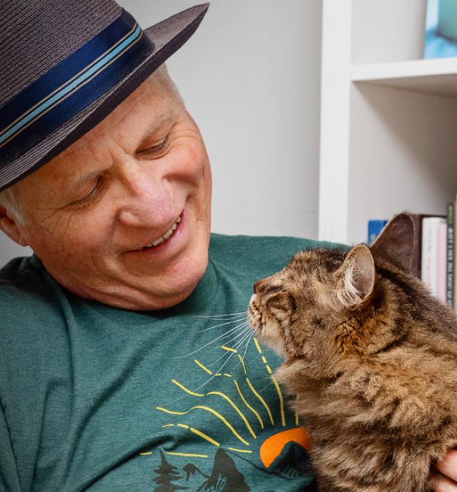 Smiling person relaxing on a couch with a cat