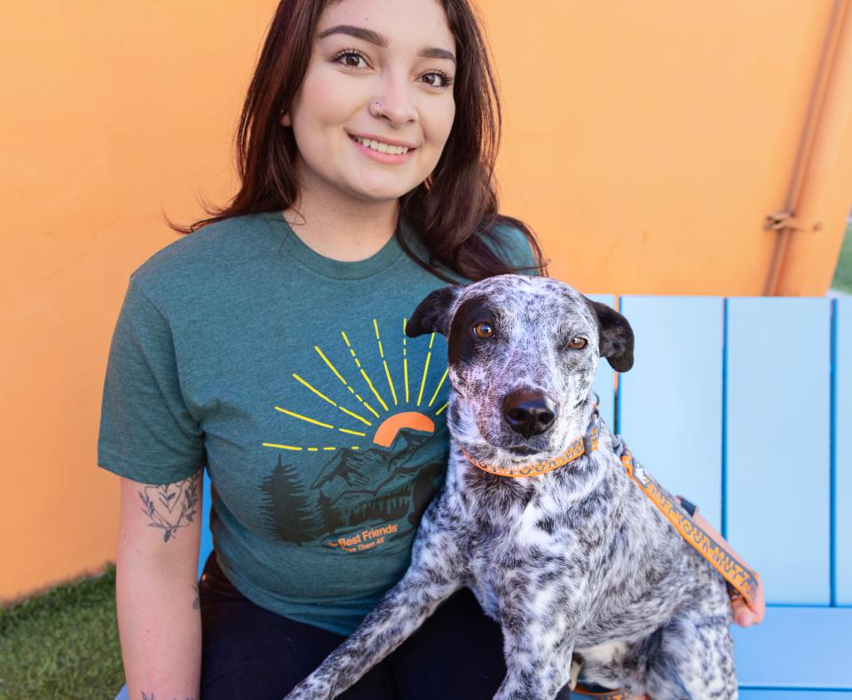 Smiling person sitting on a bench with a dog 