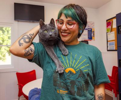 Smiling person with a cat resting on their shoulder