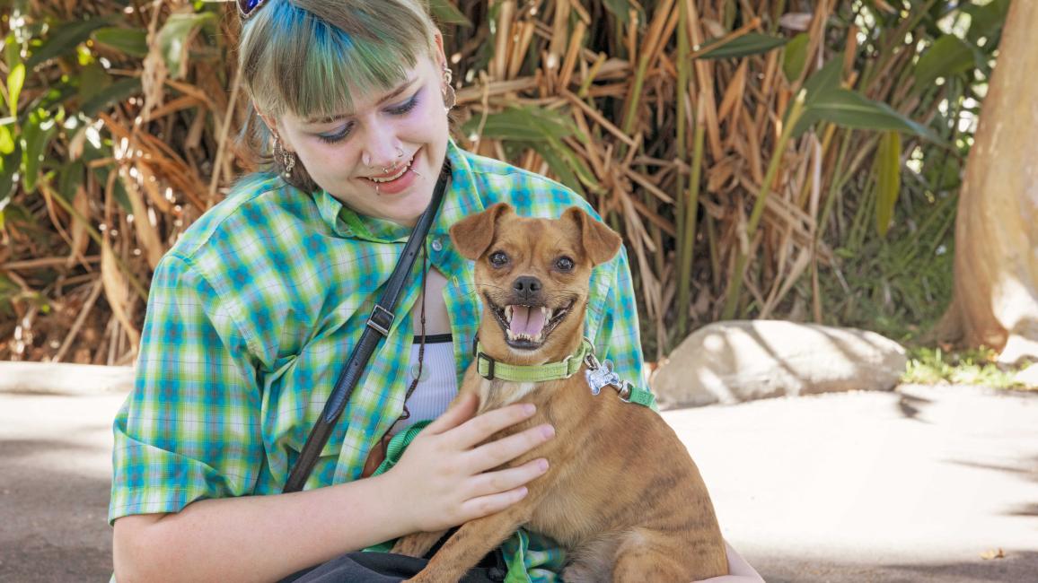 Athena holding a smiling Gremlin the dog in her lap