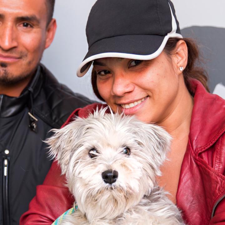 Two smiling people sitting with a recently adopted dog