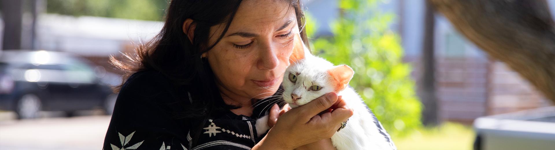 Person holding a small cat in their arms while standing outside