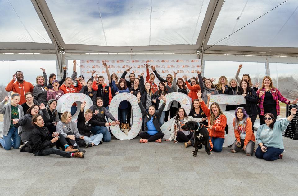 Group of people celebrating by a large statue displaying the number 2025