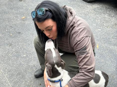 Person bending down to kiss Pluto the puppy