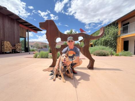 J.J. McMahon and Whitey the dog in front of a metal sculpture of a dog at the Roadhouse