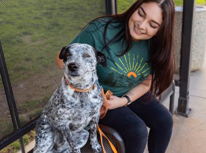 Smiling person sitting on a bench next to a dog