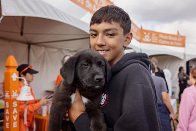 Young person holding a black puppy at the Los Angeles Super Adoption