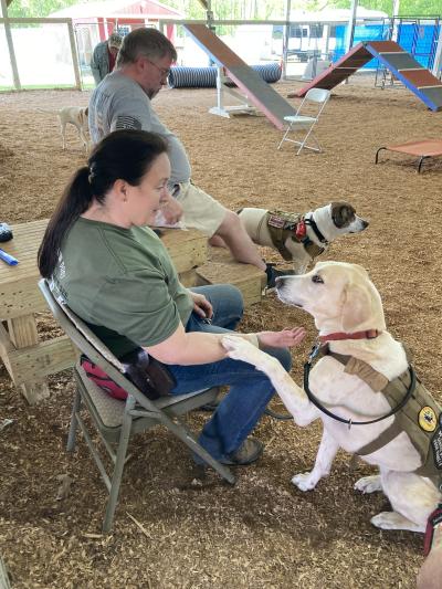 Veteran sitting in a chair with Lillie May her service dog, whose paw is up on her arm