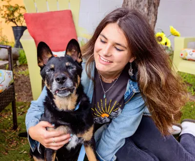 Smiling person sitting on the grass with a senior dog