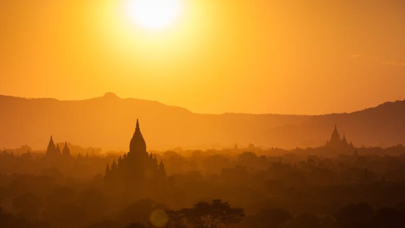 Silhouette of Bagan temples at sunset with golden skies and landscape.