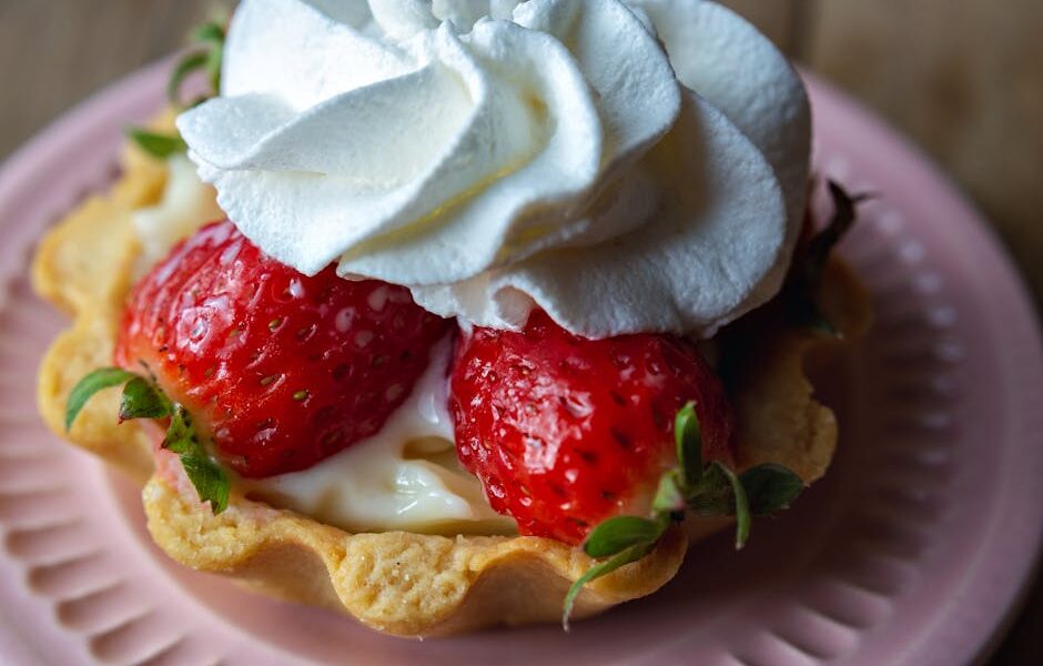 Indulge in this close-up of a strawberry tart topped with fresh whipped cream.