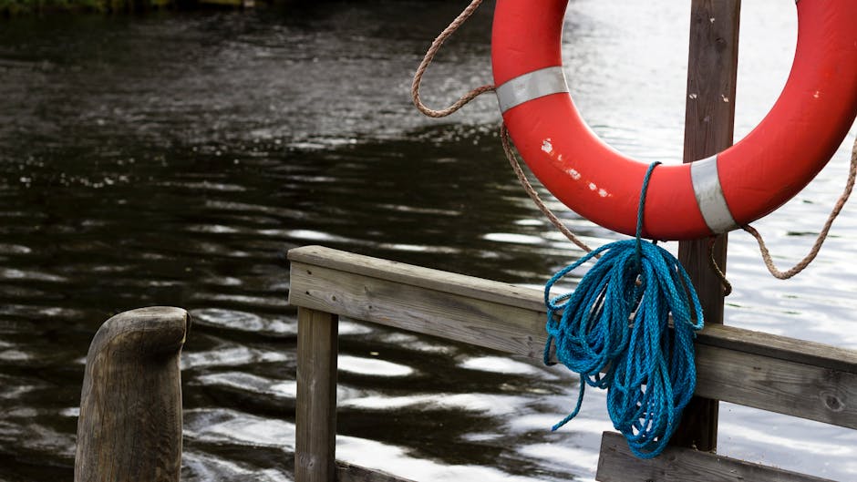 A red lifebuoy with blue rope hanging on a wooden pier by a lake in Jyväskylä, Finland.