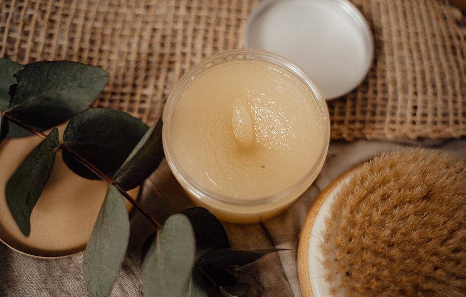 Close-up of a natural cosmetic product alongside eucalyptus leaves and a dry brush, perfect for skincare routines.