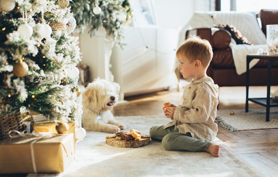Child and dog enjoying Christmas together indoors next to a beautifully decorated tree.