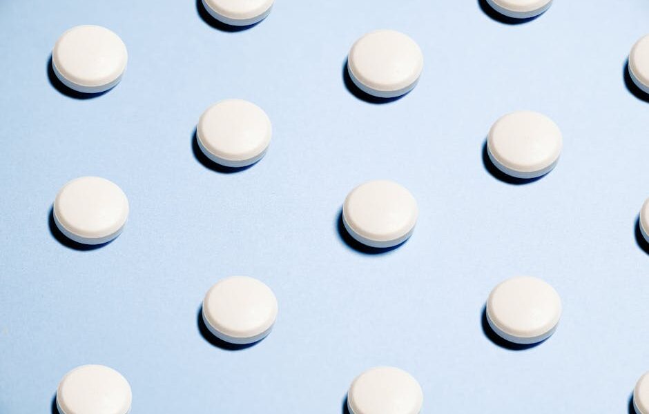 Array of white pills on a light blue background, ideal for healthcare themes.