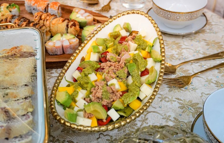 A vibrant dining table featuring sushi rolls and a fresh avocado salad, elegantly arranged.