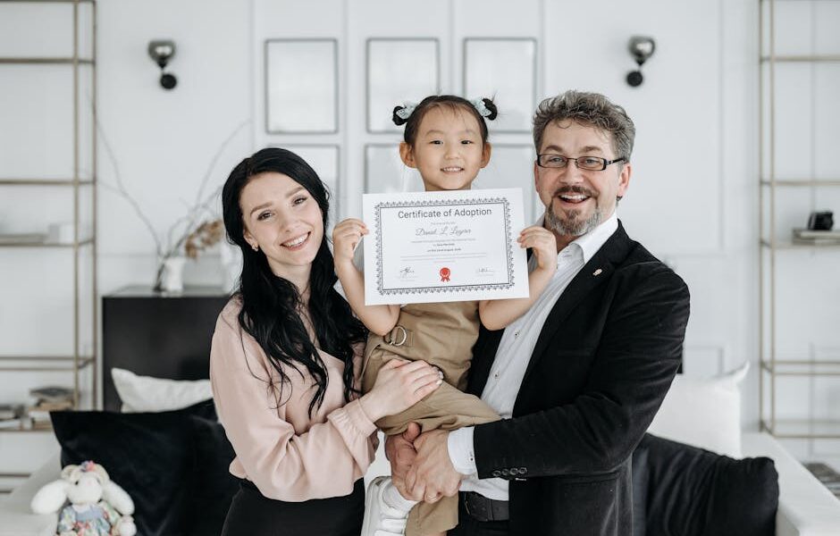Happy multicultural family celebrating adoption with certificate indoors.