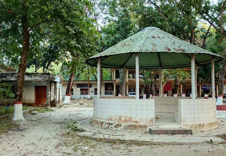 A serene outdoor view of a rustic pavilion surrounded by trees on a peaceful day.